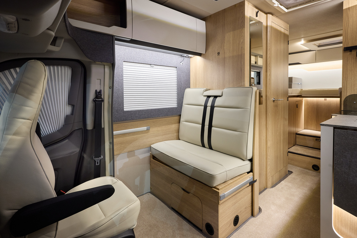 The Auto-Trail Excel 690T has beige carpet, with pale wood cabinets with white overhead lockers.  The upholstery is cream leather.  There are two steps to the rear fixed bed.