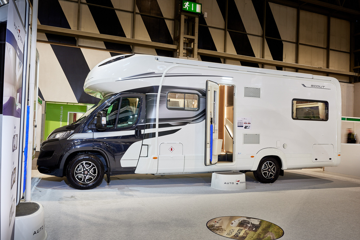 Auto-Trail Frontier Scout exterior, the motorhome has a grey cab with a white body, the habitation door is open showing into the interior, with a step to gain easy access.  There is a blue Auto-Trail umbrella in the door.