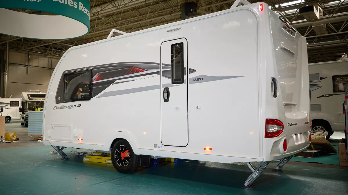 Swift Challenger Grande SE 480's exterior is white with grey and red graphics.  The caravan is a single axle and has its corner steadies down.