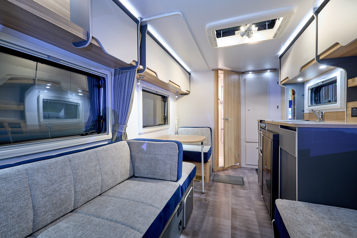 Bailey Discovery D4-4L interior, grey and blue upholstery, pale wood cabinets, open skylight, wooden door which is slightly open