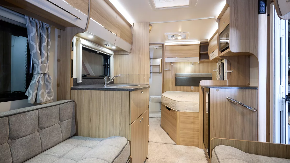 Bailey Phoenix+ 440 interior, grey upholstery, light wood/cream overhead lockers, lounge, fixed bed, washroom, two skylights