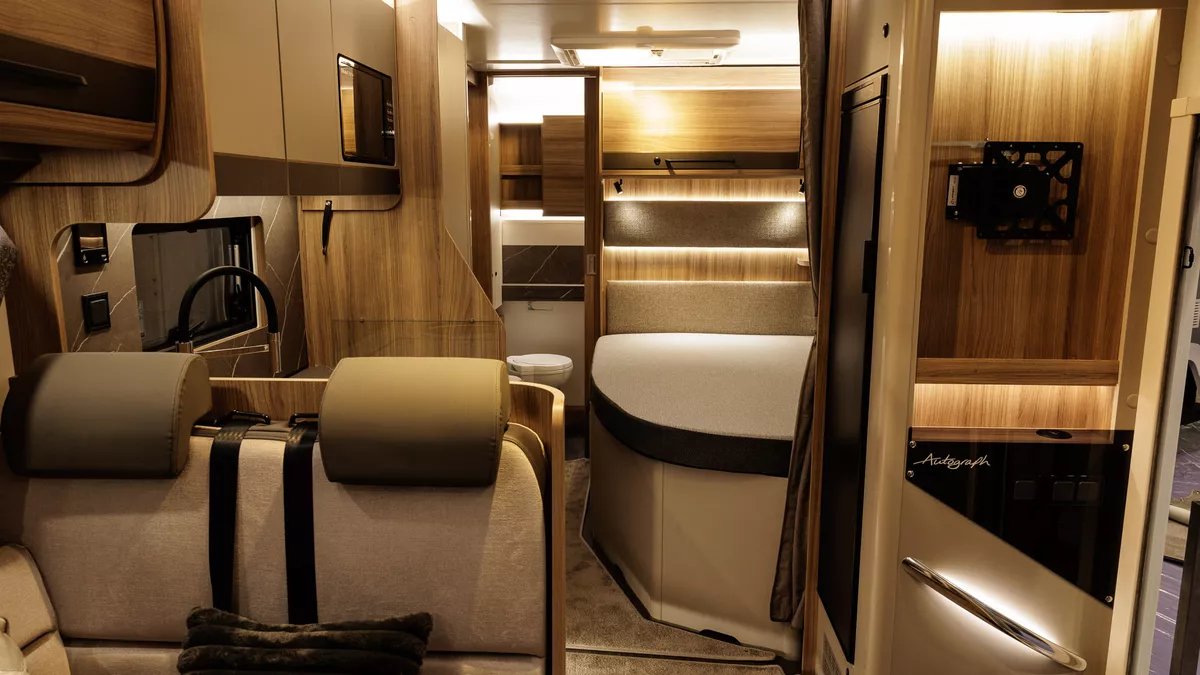 The Bailey Autograph 79-4F has beige and brown upholstery.  The rest of the interior matches these shades.  There is a fixed bed and there is a brown privacy curtain to separate the bedroom.  The washroom is at the rear.
