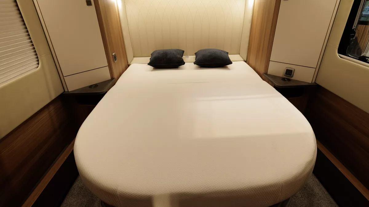 The Auto-Trail Frontier Comanche has a rear fixed island bed with two black cushions on either side.  There are two windows,