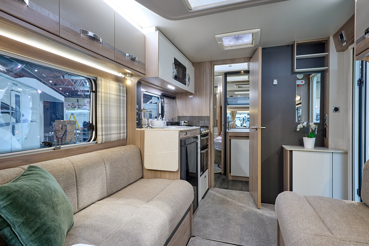 Swift Challenger Exclusive 560's interior has pale wooden furniture with beige upholstery.  The washroom is in the centre of the caravan with the bedroom at the rear.