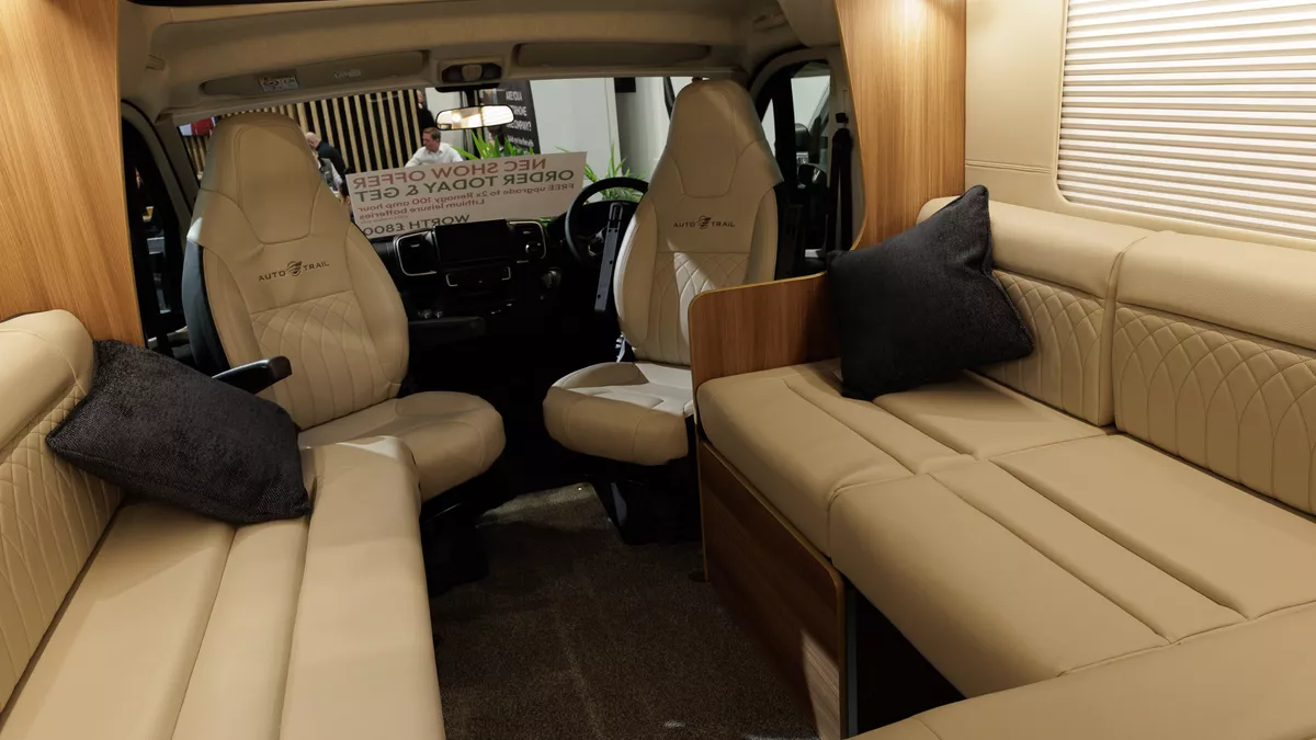 The Auto-Trail Frontier Comanche has cream leather upholstery and the two front seats are swivelled to join the lounge area.  There are two black cushions in the corners of the sofas.