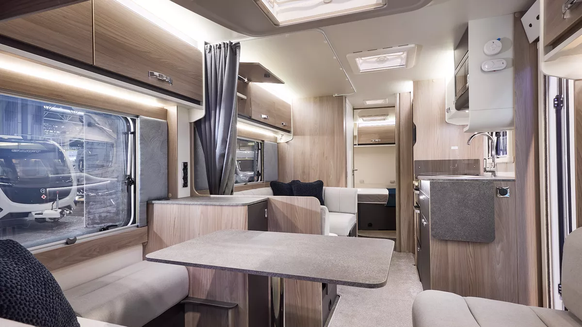 Interior of the Swift Challenger Grande 630 with beige sofas, cosy cushions and beige carpets.  The large windows and three sky lights will let natural light flood in.  The dinette is opposite the kitchen.