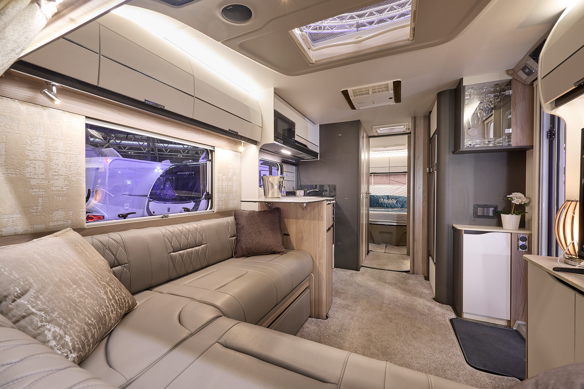 Swift Elegance Grande 860's interior has tan leather upholstery with pale cabinets.  The kitchen is placed in the centre with the washroom just beyond.  There is a rear bedroom and its door is open.