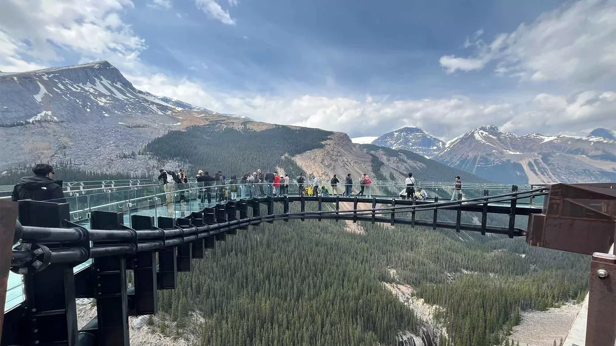 Looking out at the Skywalk high above the trees below with the high  partially snow covered peaks