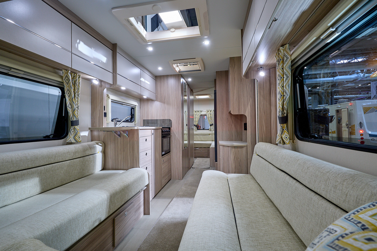 Xplore 585's interior has wooden furniture and has cream sofas with black piping.  There is a central kitchen.  There is a second lounge to the rear.