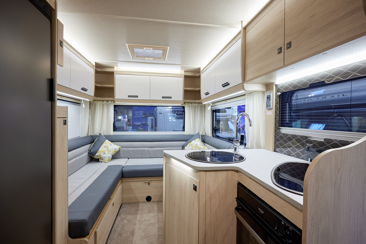 Auto-Trail F-Line F68 has two tone upholstery, with pale wooden furniture.  There is a round sink, hob with cover and oven in the kitchen.  The overhead lockers are pale wood and white.  
