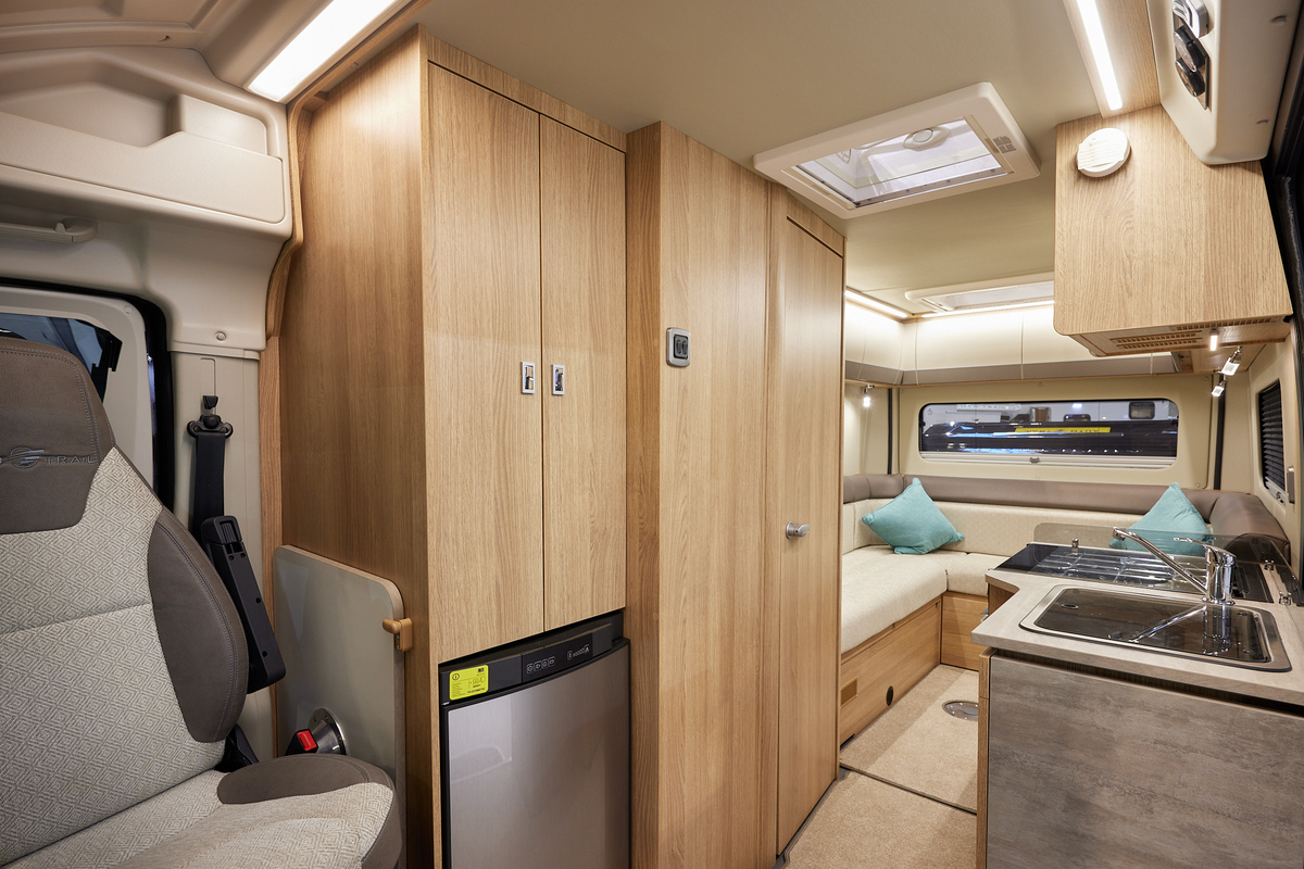 Auto-Trail V-Line 610 Sport has cream upholstery, with wooden furniture.  The floor has beige carpet.  The overhead lockers are cream.  The kitchen has a square sink and a flap to extend kitchen work surface.  The vehicle has a rear lounge.