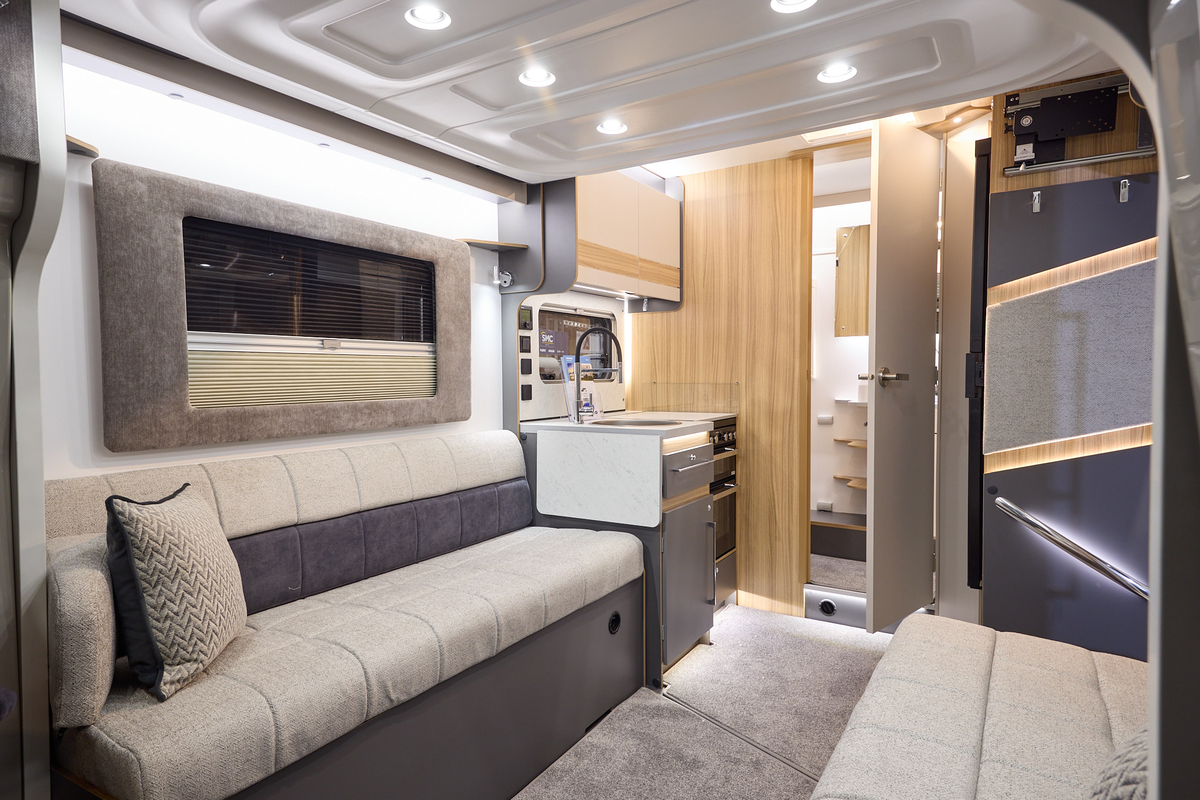 The Bailey Adamo 60-2 has grey carpets, with cream and pale wood cabinets.  The upholstery is cream and dark brown.  There is a step to the rear washroom.  There is a mid brown plinth around the lounge window.