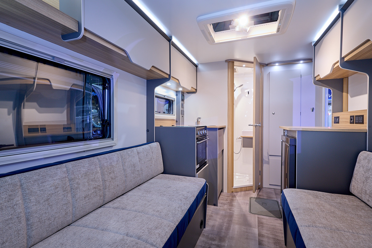 Bailey Discovery D4-2 interior, grey upholstery, pale wood cabinets, open skylight, wooden door which is open revealing the washroom
