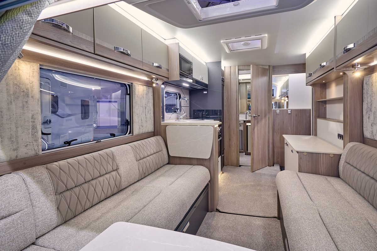 Swift Challenger Exclusive 480’s interior has wooden units with beige upholstery which has embossed patterns.  The rear door is open revealing the washroom