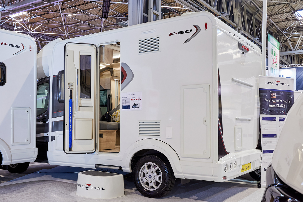 Auto-Trail F-Line F60 exterior, the motorhome is white, the habitation door is open showing into the interior, with a step to gain easy access.  There is a blue Auto-Trail umbrella in the door.