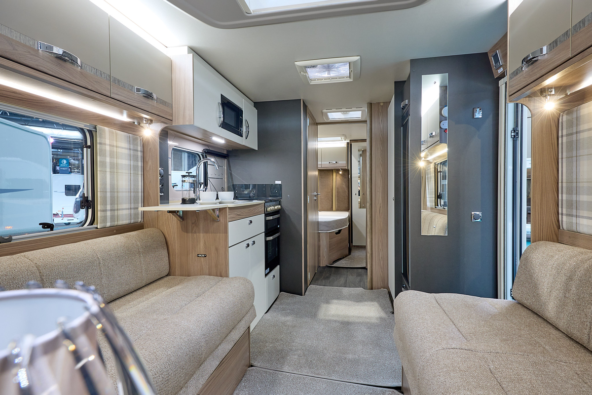 Swift Challenger Grande SE 670's interior has pale wooden furniture with beige upholstery.  The washroom is in the centre of the caravan with the bedroom at the rear.