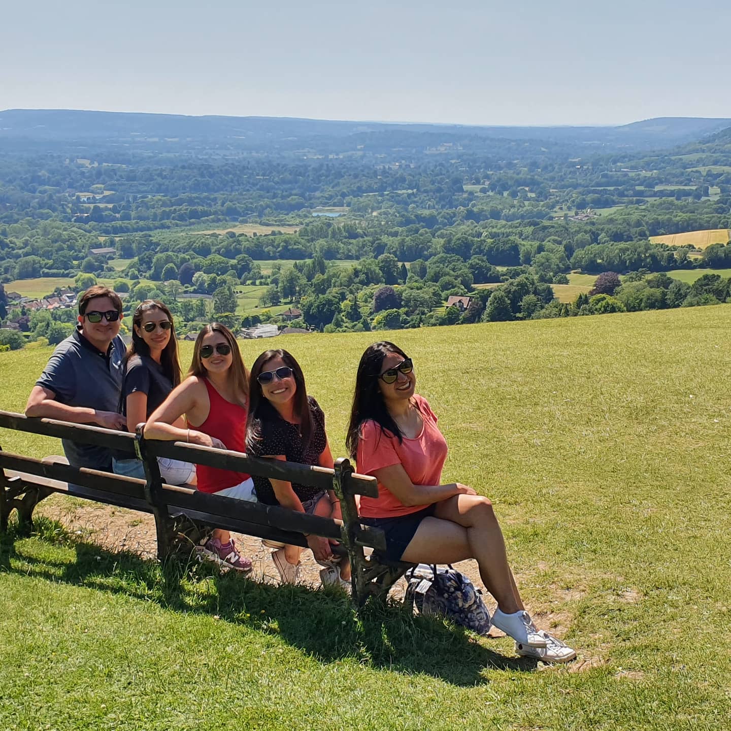 Five people sitting on a bench overlooking the Surrey Hills