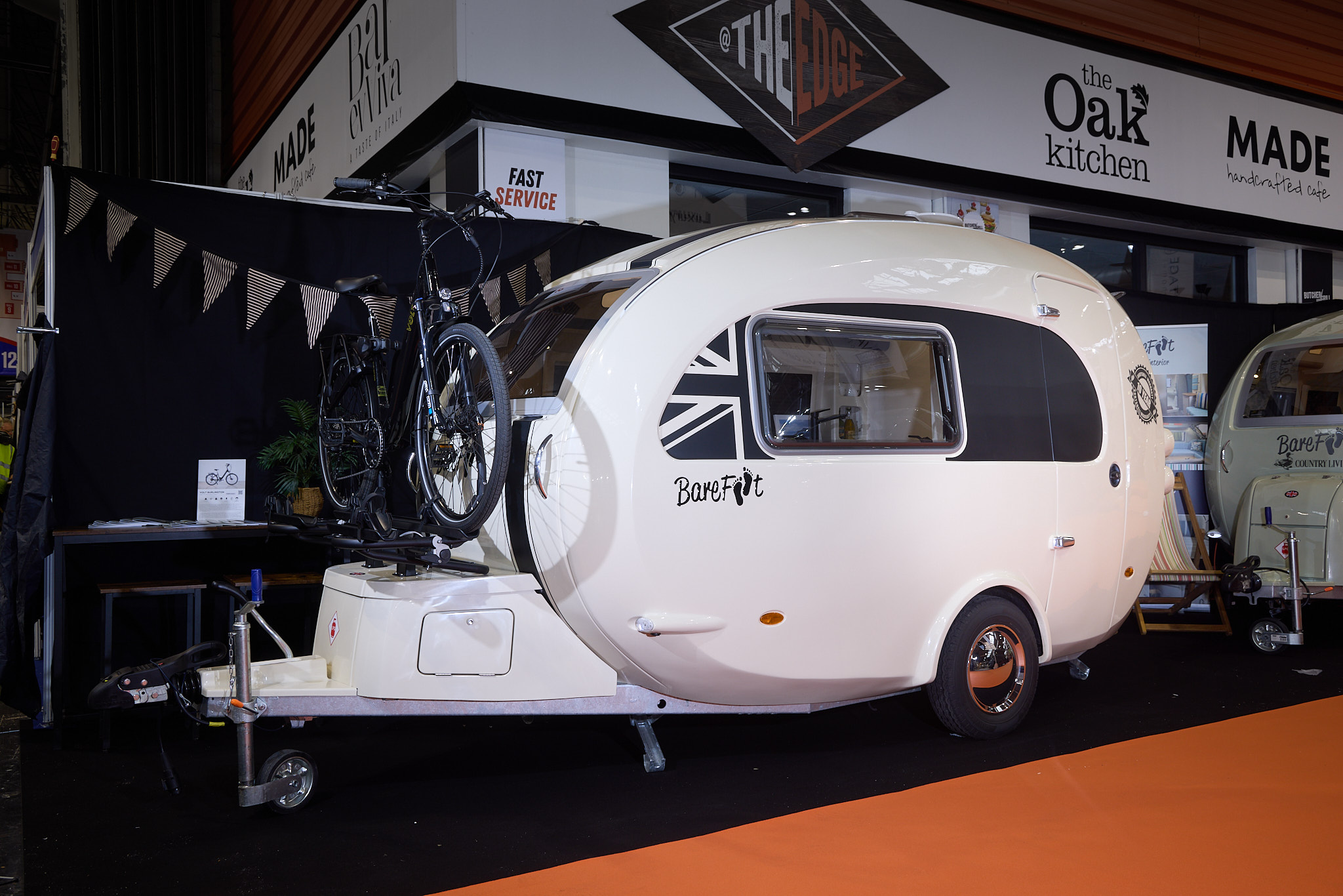 Barefoot Caravan Eclipse’s exterior is white with a black panel around the window with a part Union flag.  There is a mountain bike on a fitted bike rack over the locker at the front.
