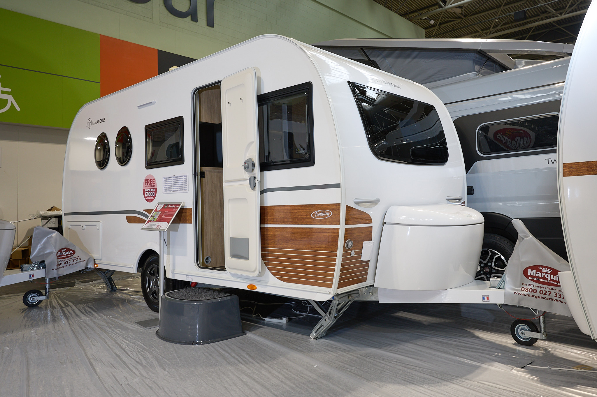 La Mancelle Fantaisy 440CL exterior is white with brown panels to the bottom of the front panel.  The door is open and there's a grey step to gain easy access to the interior.