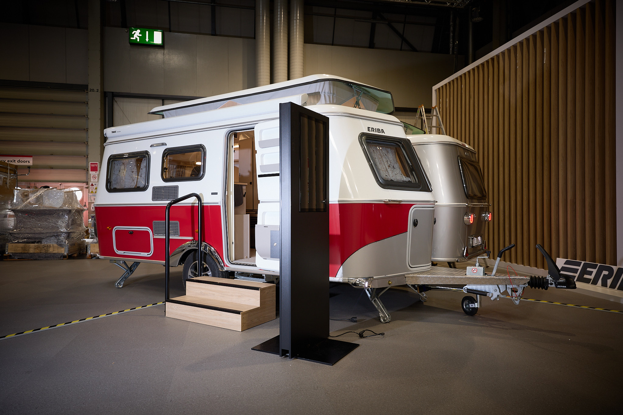 Eriba Touring 530 Urban Tango Red's exterior is white and red.  The pop top roof is open.  There are two wooden steps into the interior.