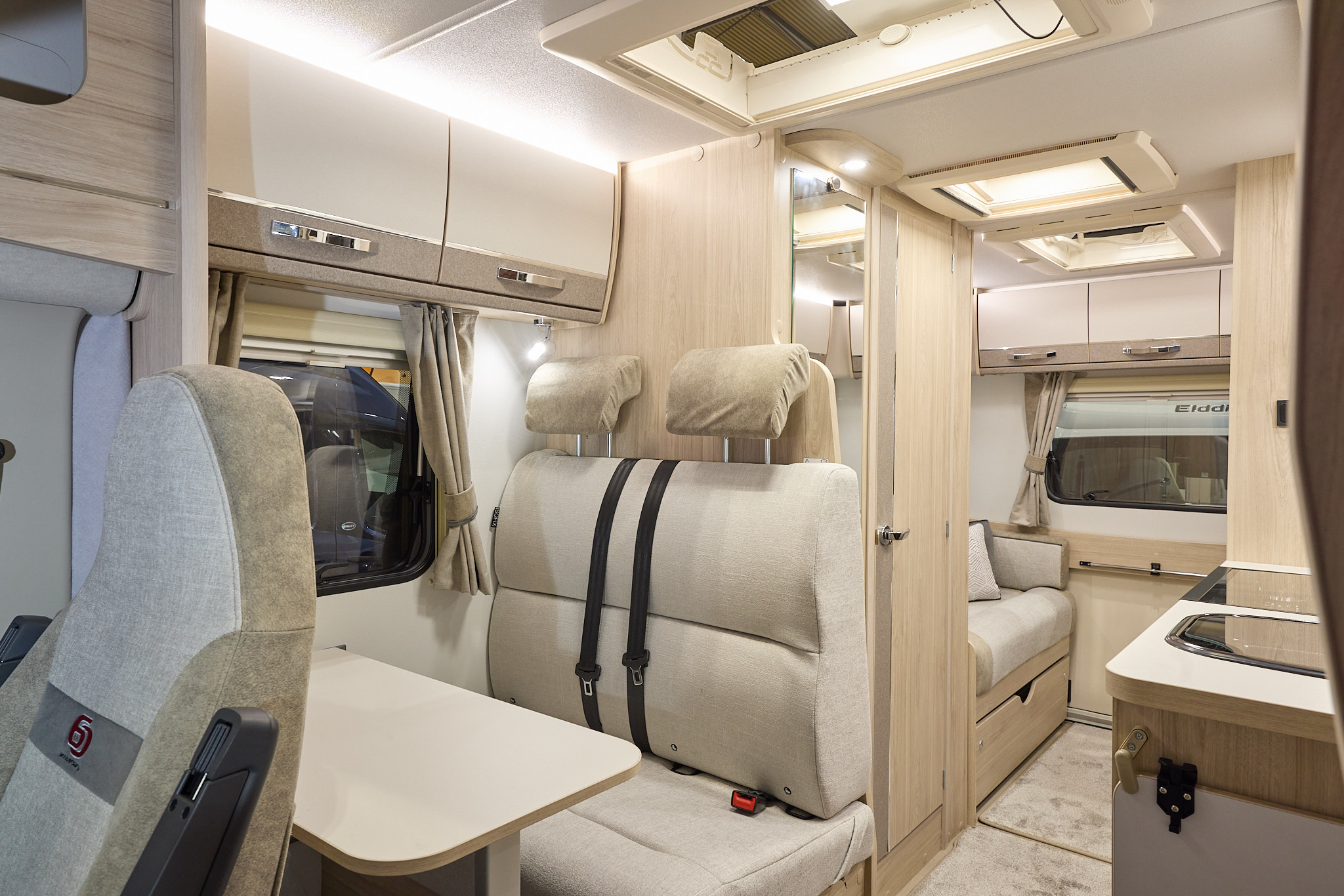 The Elddis Accordo 135 has a beige carpet, with cream and pale brown cabinets.  The upholstery is cream and pale brown.  There are three skylights.  There is a rear lounge.