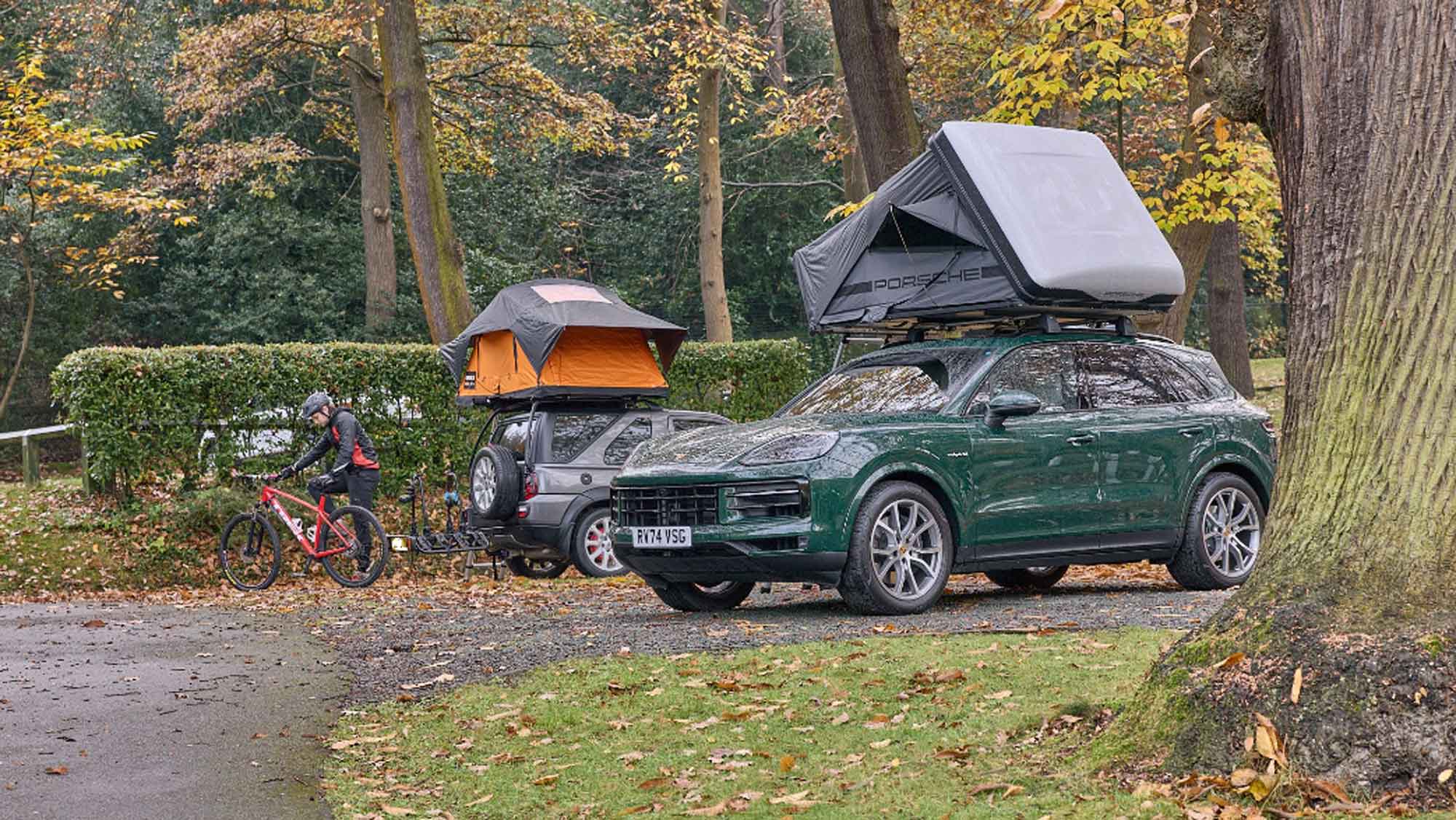 Two cars with roof tents with people on bikes