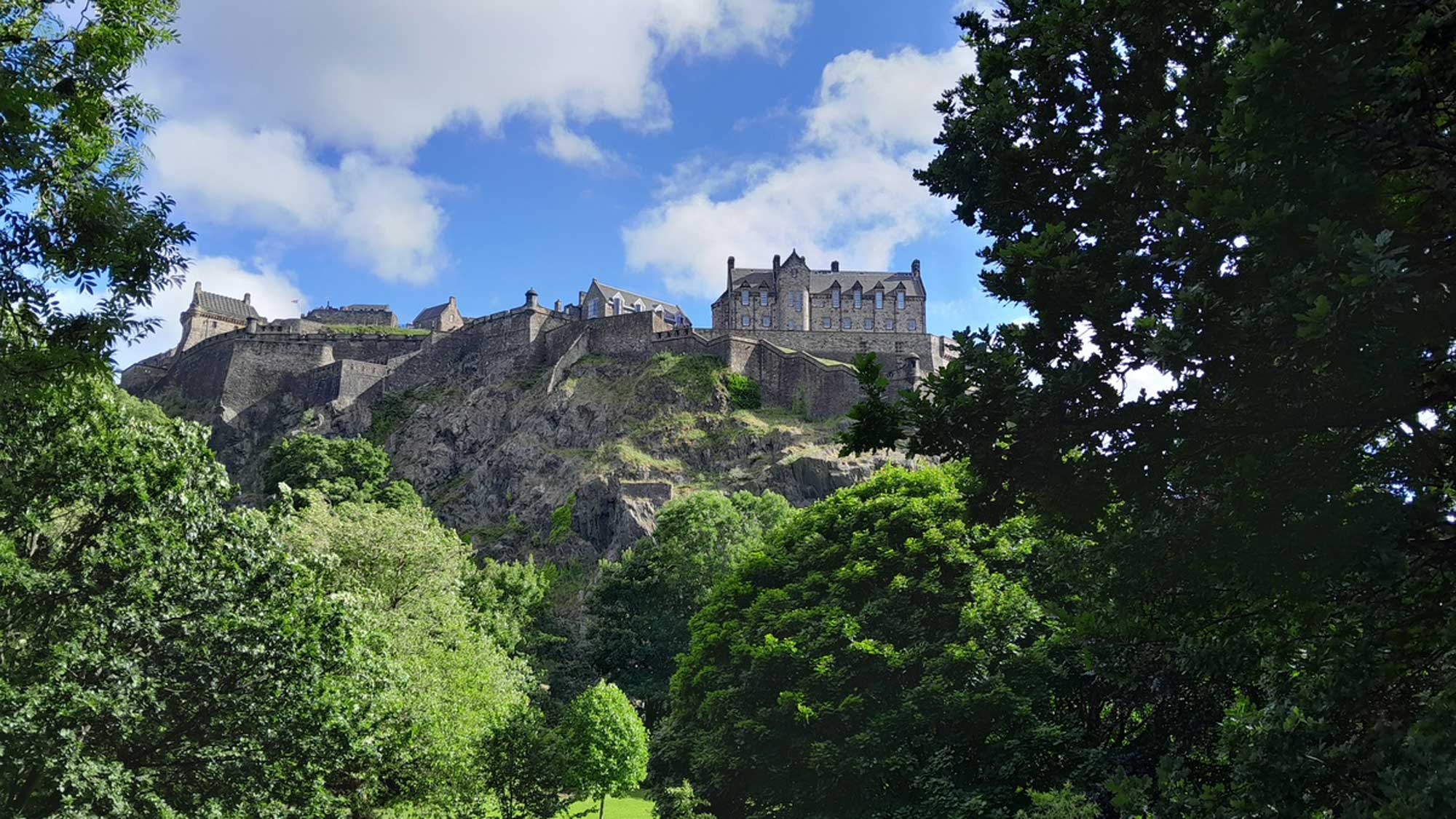 view of the old city of Edinburgh at the top of the hill with the treetops below