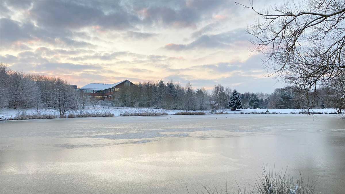 Image of a frozen lake in winter, large cabin in the background