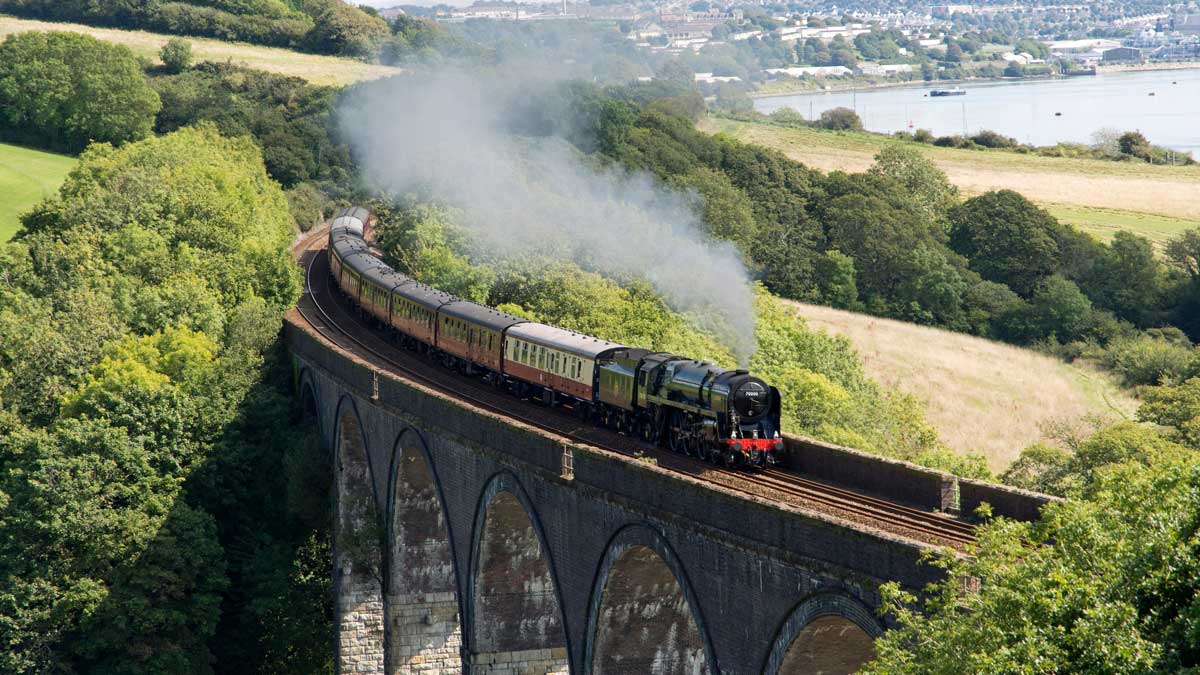 Steam train travelling at speed across Forder Viaduct, in Cornwall, UK