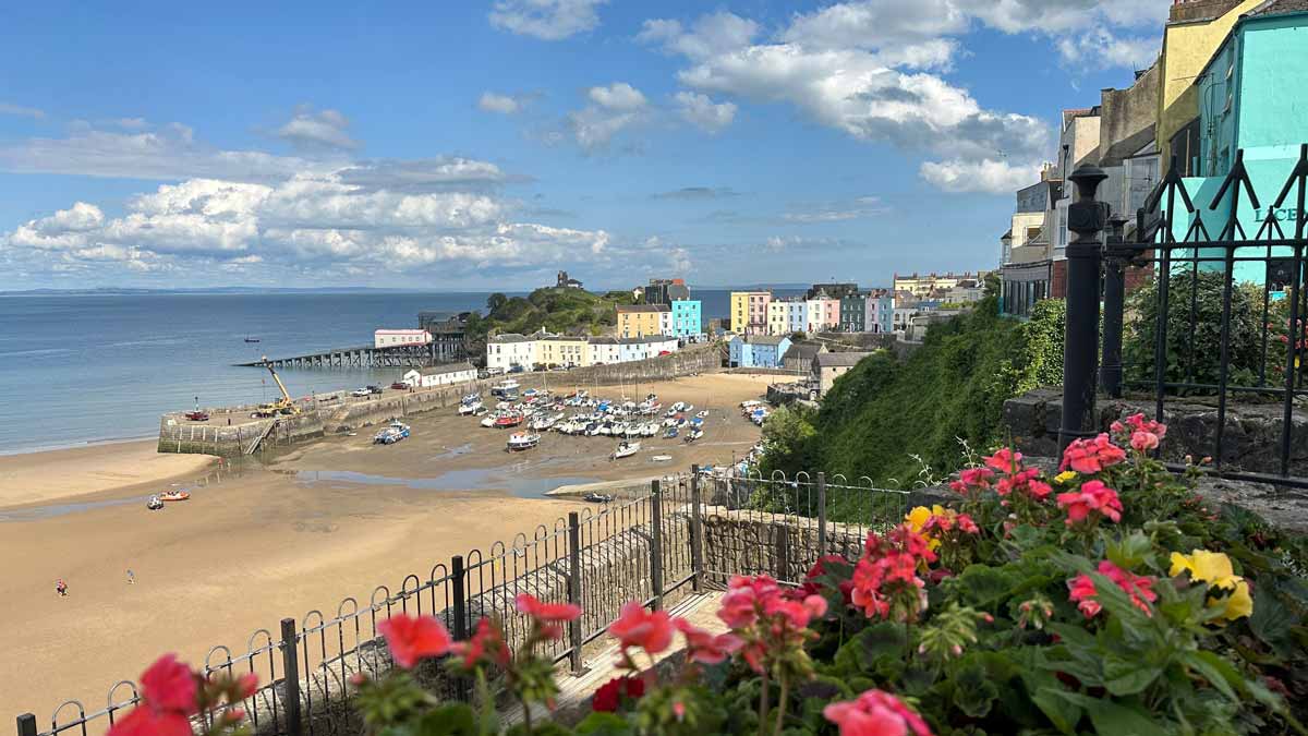 Tenby Harbour under a blue sky with poeple on the sandy beach