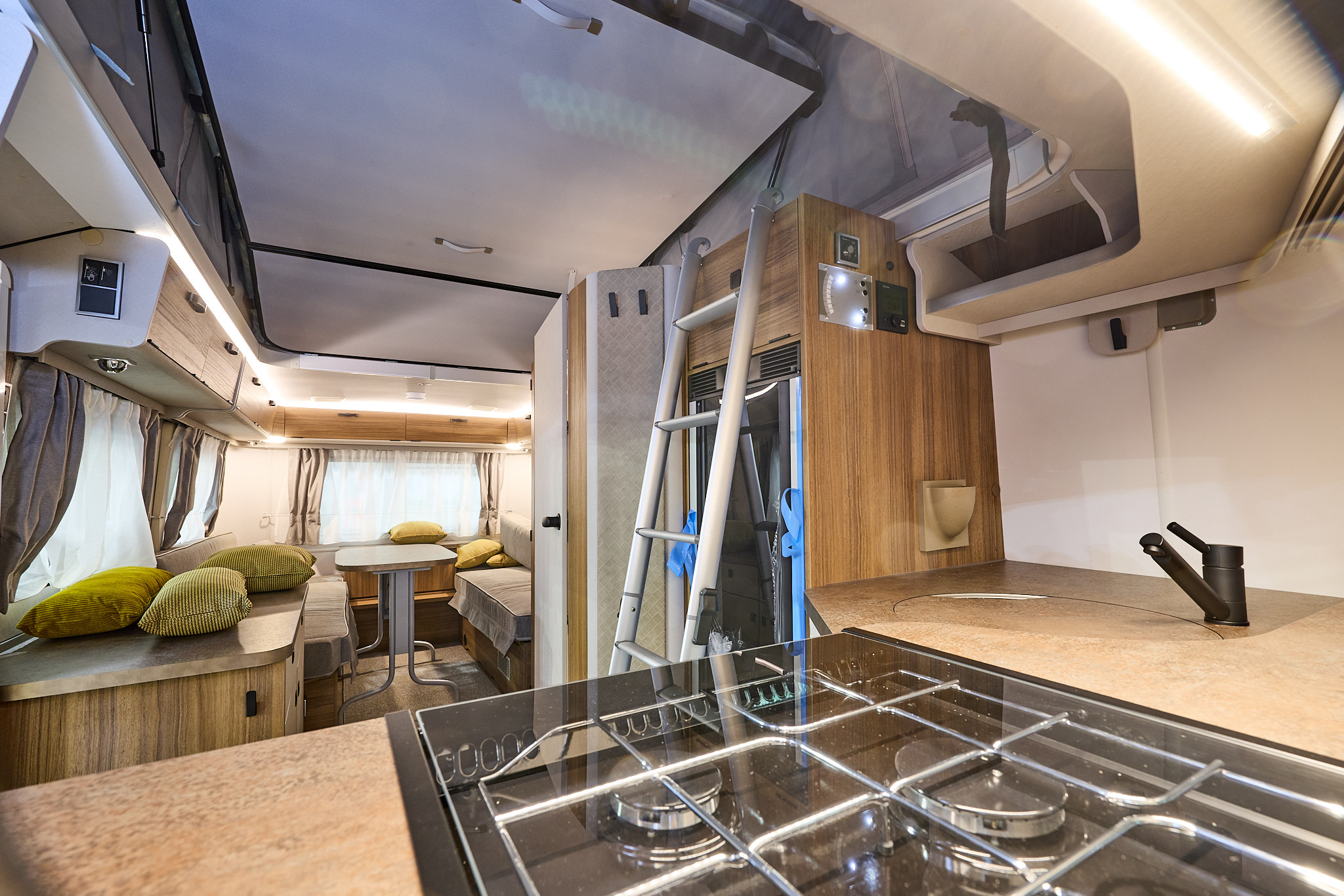 Eriba Touring 620 Legend’s interior has a kitchen at the front with two sofas and a table to the rear.  There is a silver ladder with access to the bed in its pop top roof.