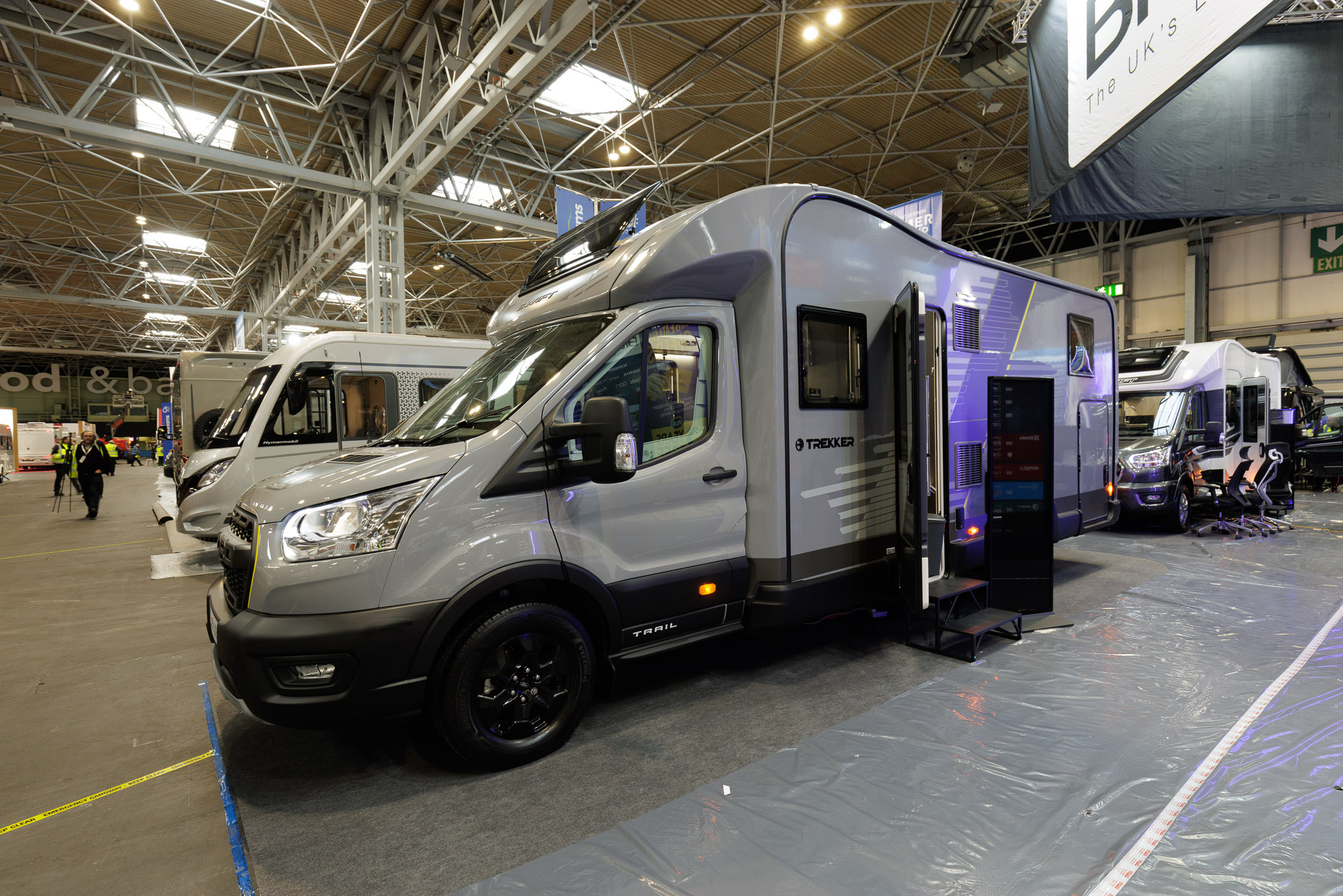 The Swift Trekker 584 is grey, its habitation door is open and there are two black steps to gain access.  There's an information board next to the steps.