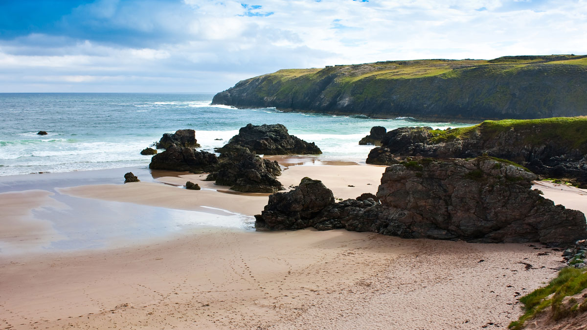 Rocky beach landscape with white sand and blue sea