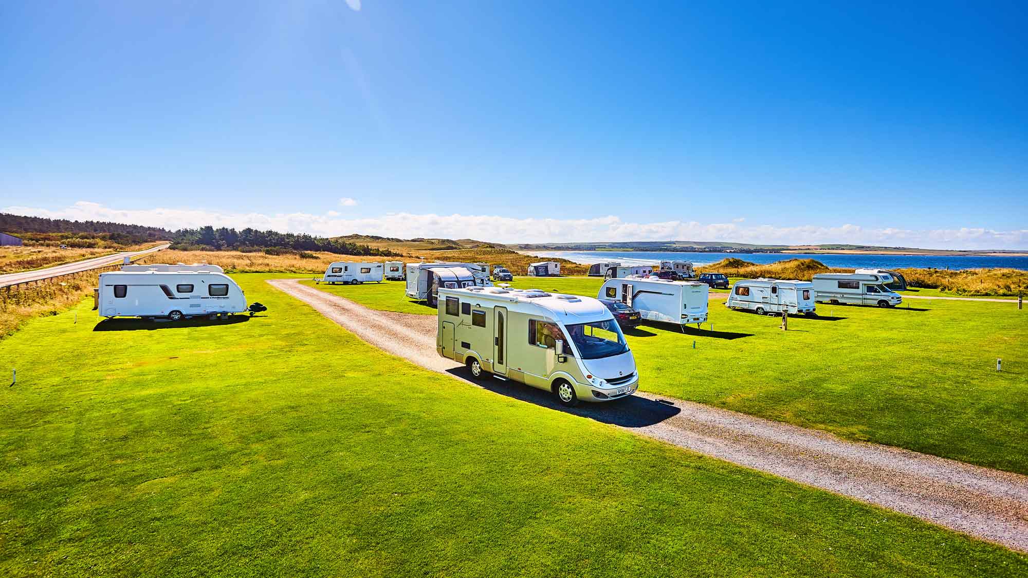 Dunnet Bay campsite with caravans and motorhomes parked on cut grass overlooking bay