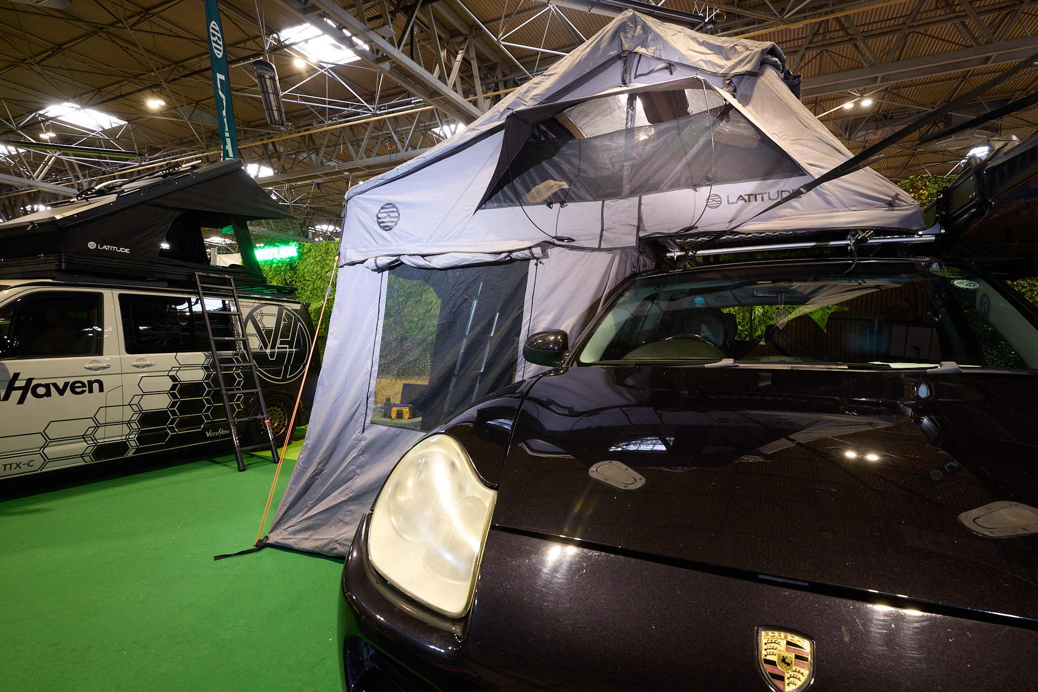 The Latitude Tents Pioneer XL is displayed on a black Porsche.  It has grey canvas walls and a pale grey roof.  It also has an awning.  