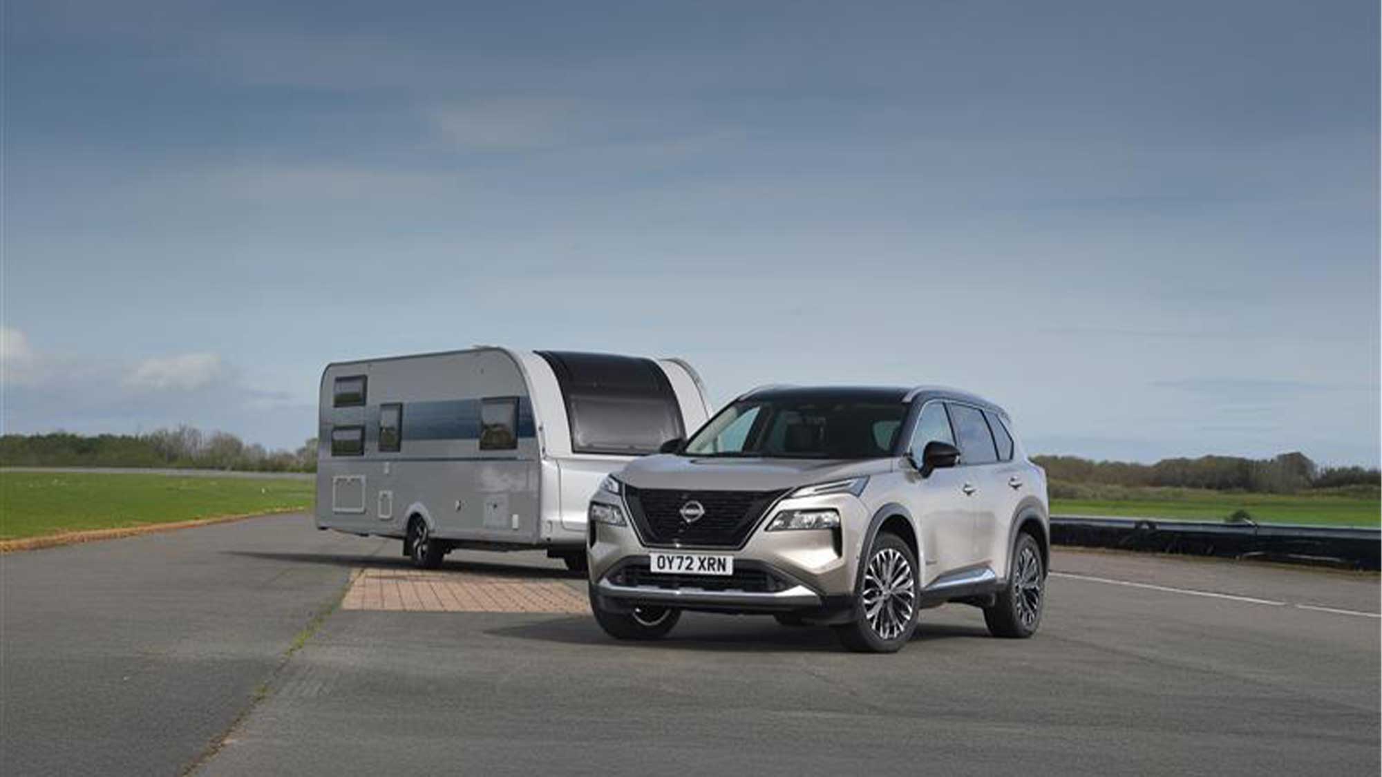Silver Nissan car in the foreground with a caravan at an angle behind
