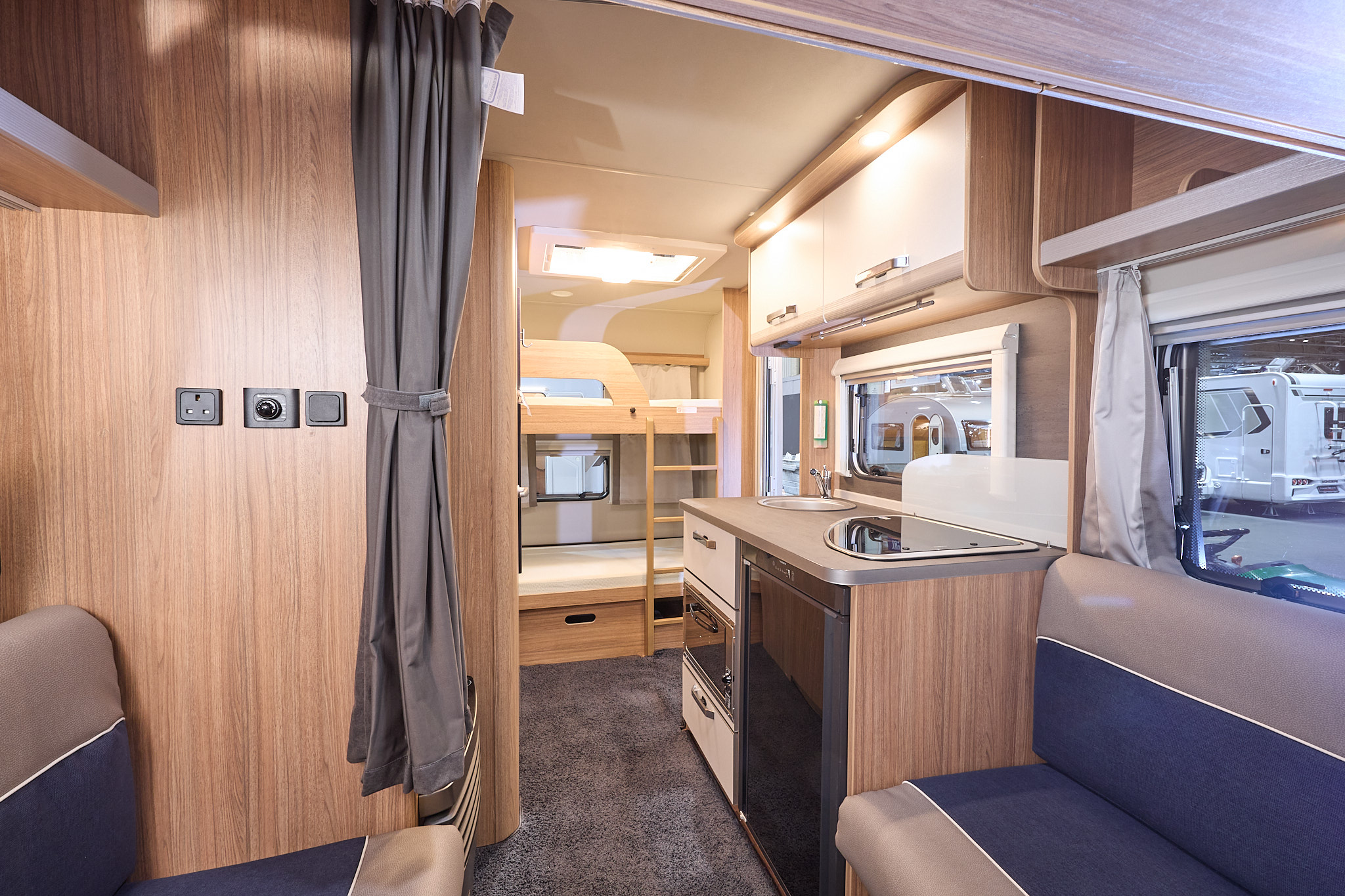 Weinsberg CaraOne 400 LK Bunks' interior is wooden with two tone sets in brown and blue.  The bunks are at the rear and there is a ladder for access to the top bunk.