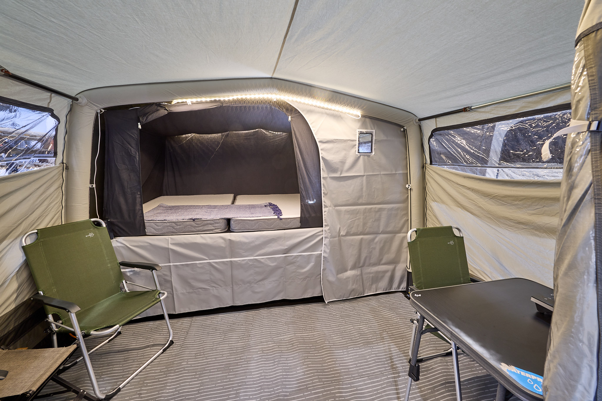 Campmaster AIR 1000 LX interior, cream canvas, the sleeping area is unzipped.  There are two lime green canvas chairs.