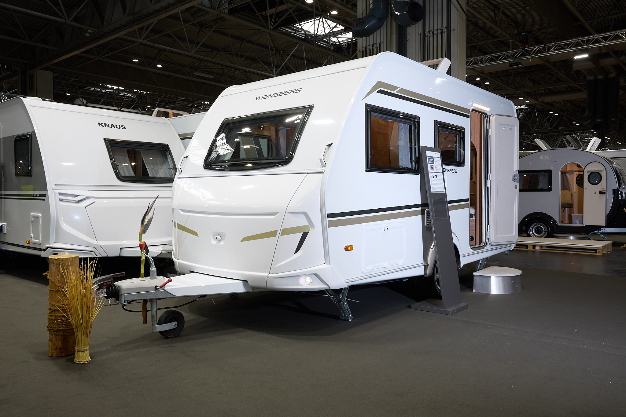 Weinsberg CaraOne 400 LK Dinette's exterior is white with brown and gold graphics.  The door is open and there is a step to enable easy access to the interior.