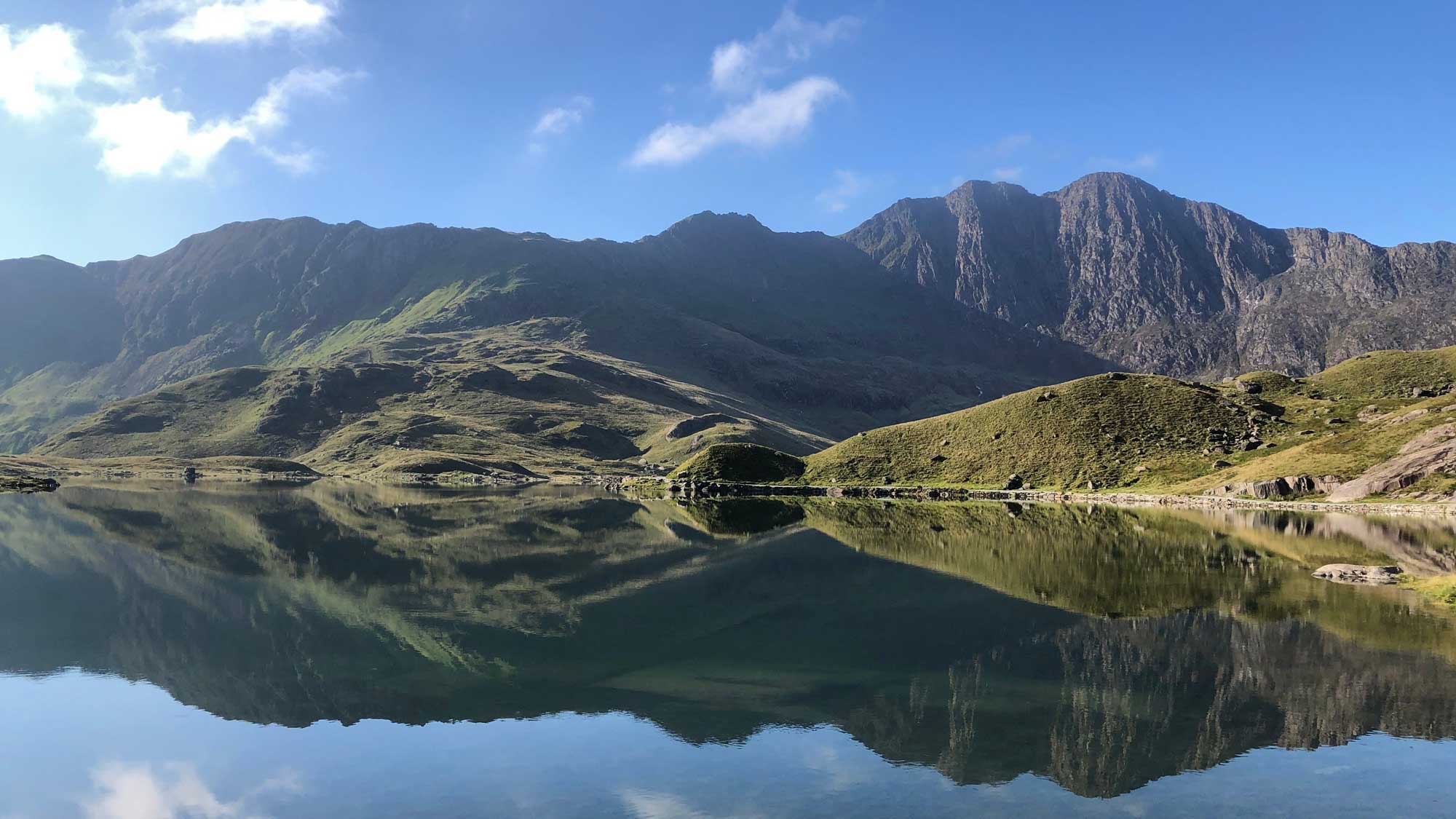 the slopes of Yr Wyddfa reflected in the mirror-smooth water of the lake