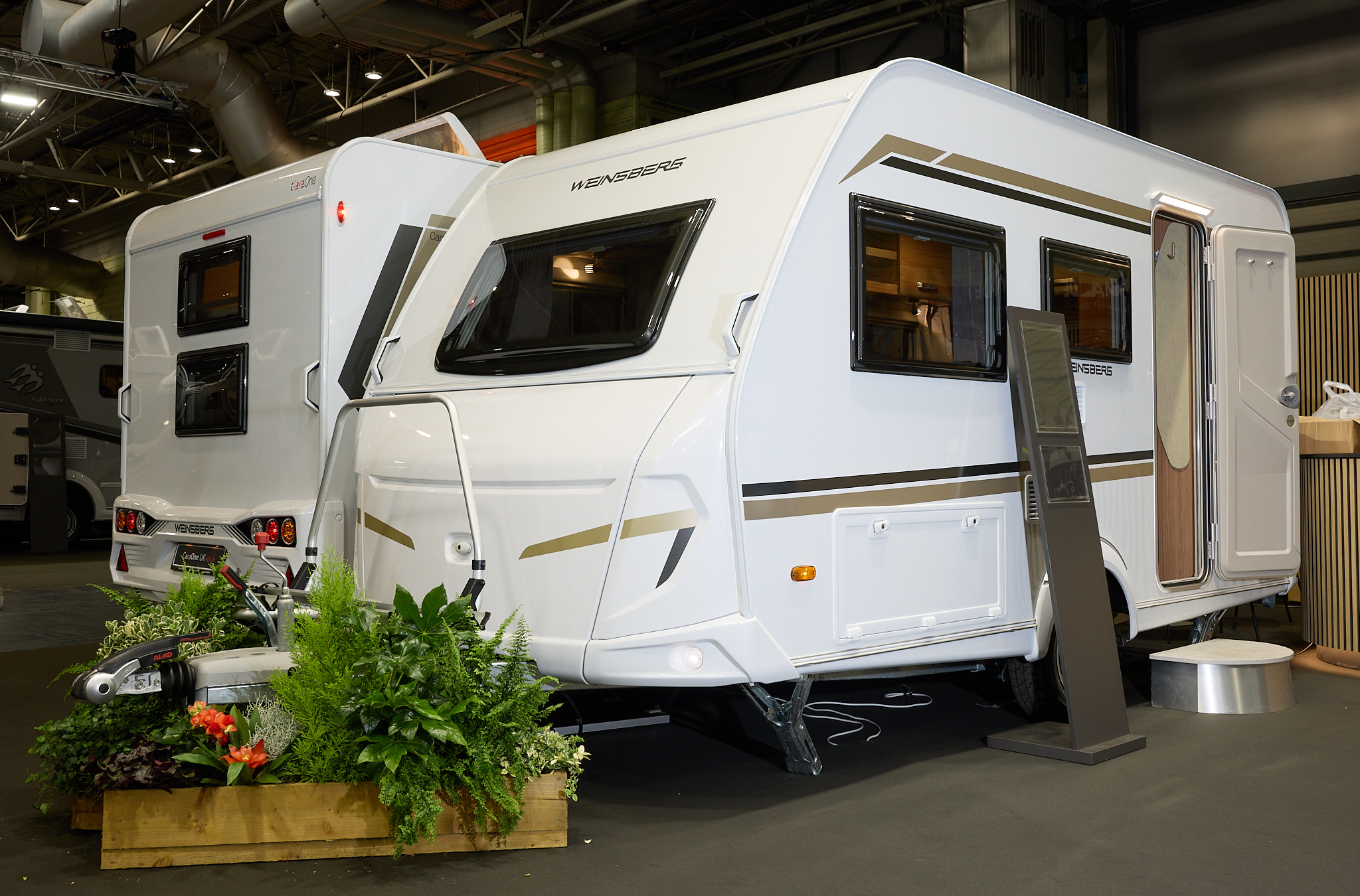 Weinsberg CaraOne 390 QD's exterior is white with brown and gold graphics.  The door is open and there is a step to enable easy access to the interior.