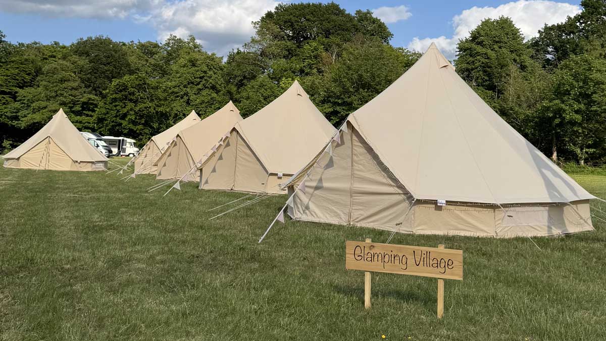 neat little bell tents lined up in the glamping village with bunting outside each