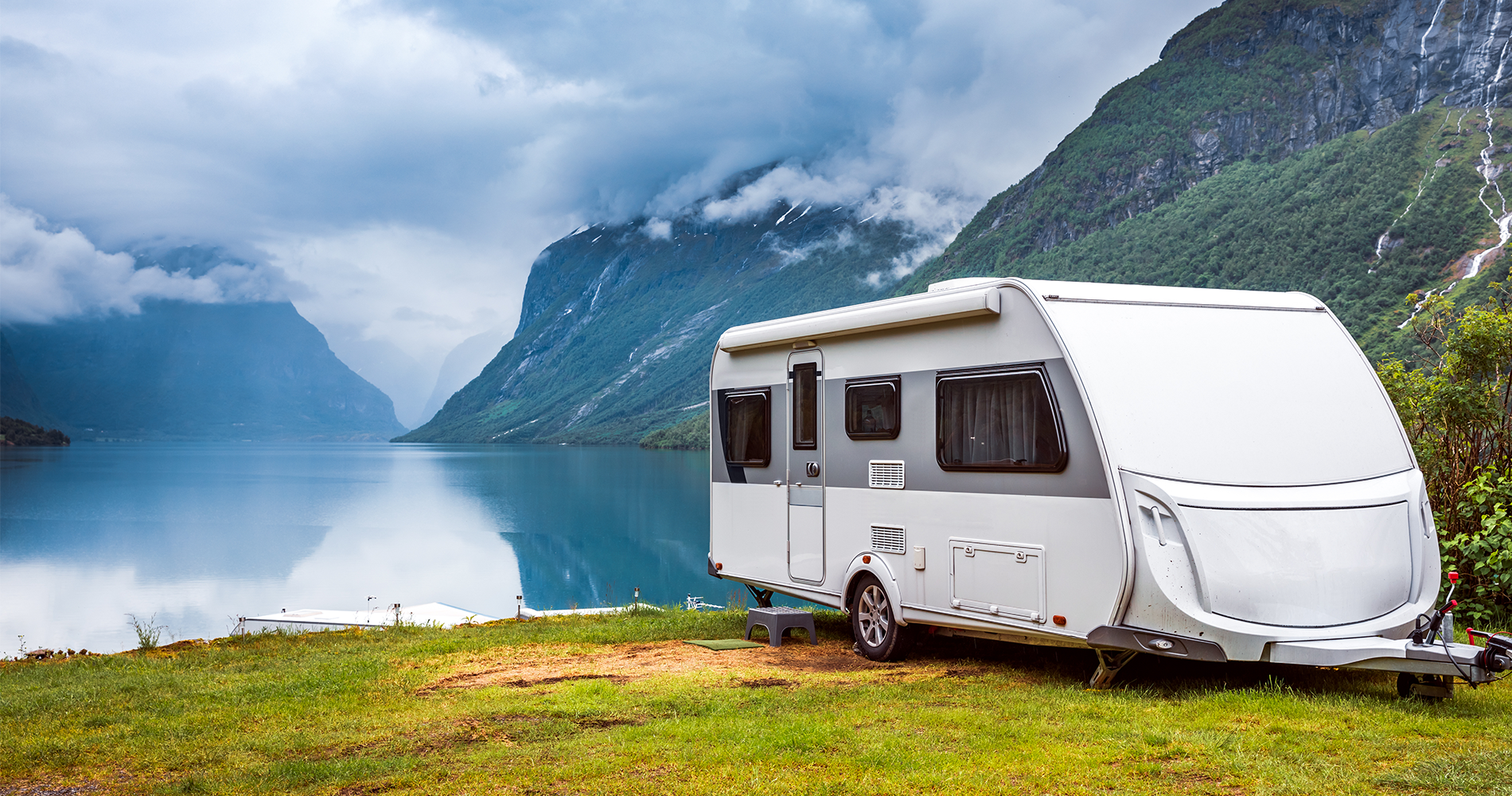 caravan sitting by a lake by mountains