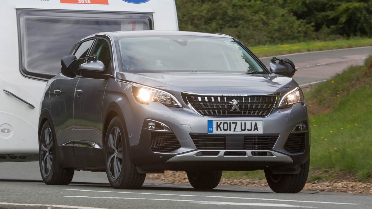 Side view of a silver Peugeot towing a caravan