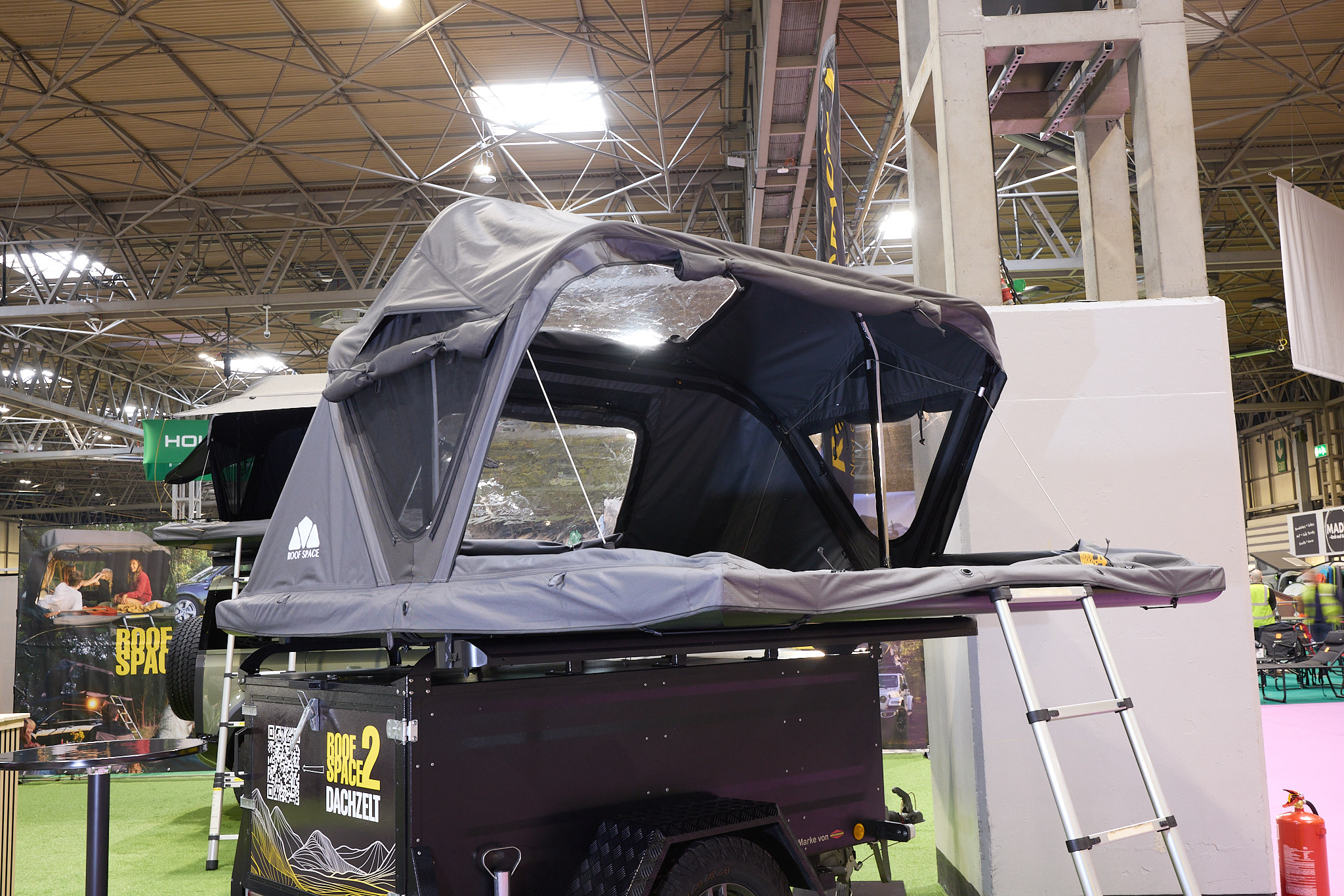 The Roof Space 2 is fully extended on a trailer.  The canvas is pale grey.  There is a platform with a sturdy ladder to gain easy access.