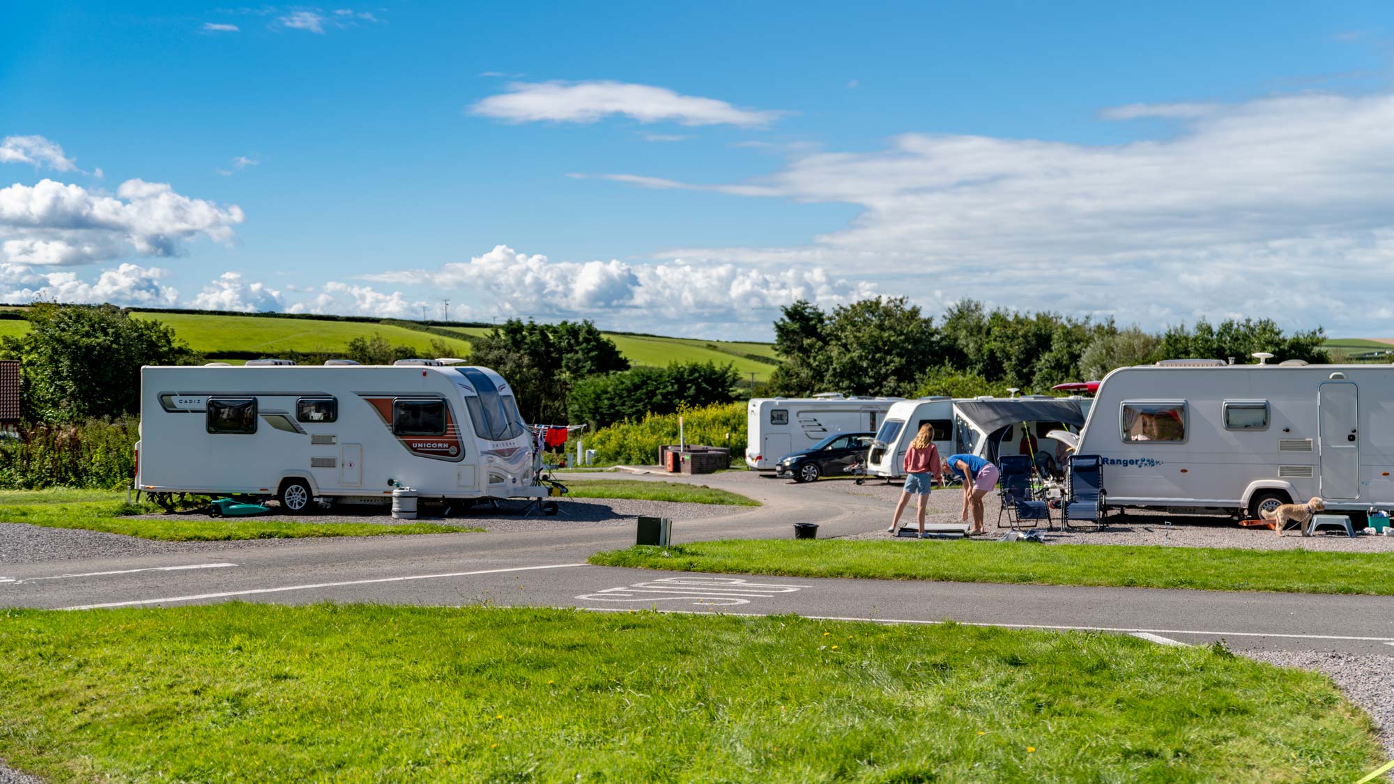 Family of three outside their caravan on a sunny day