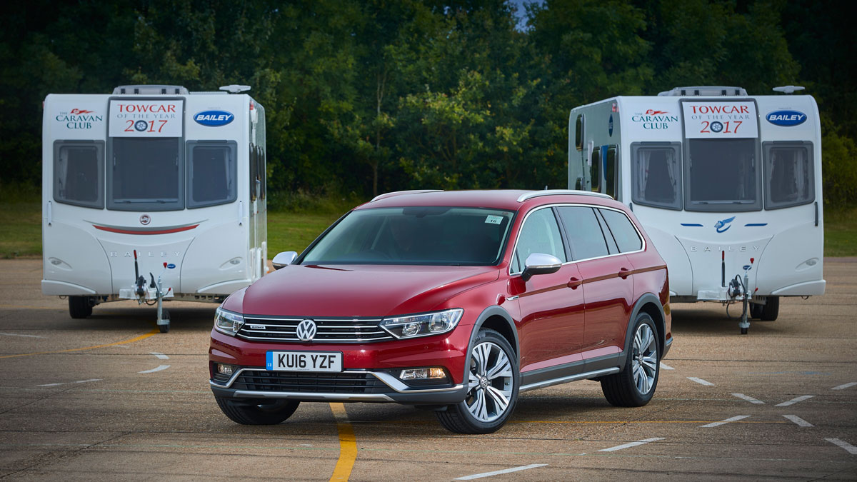 Red VW parked in front of two caravans