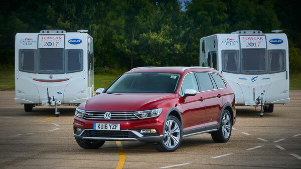 Red VW parked in front of two caravans