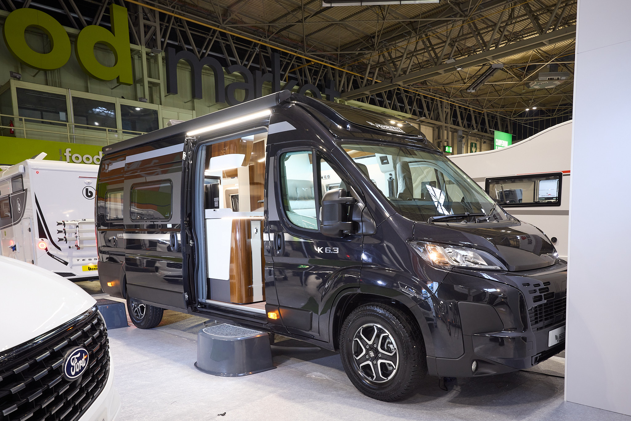 The Mobilvetta Admiral K6.3 is black with gold decals.  There is a black step by the open sliding habitation door which reveals the interior.