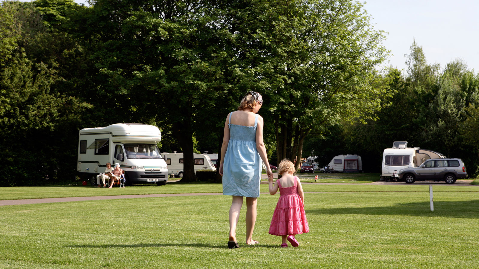 Mother and daughter walking on grass at Cirencester Park